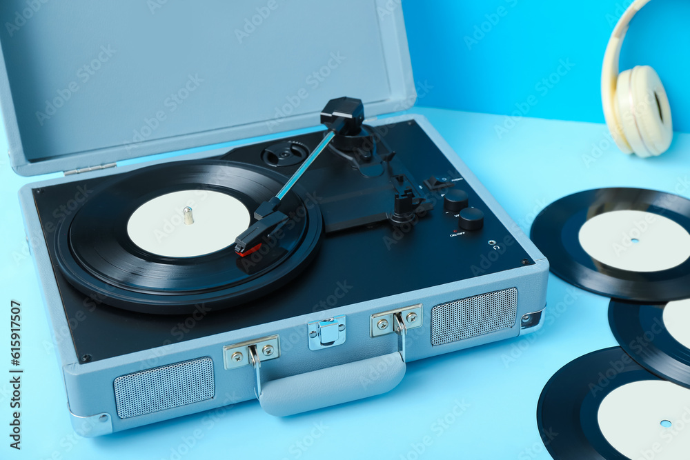 Record player with vinyl disks on blue table