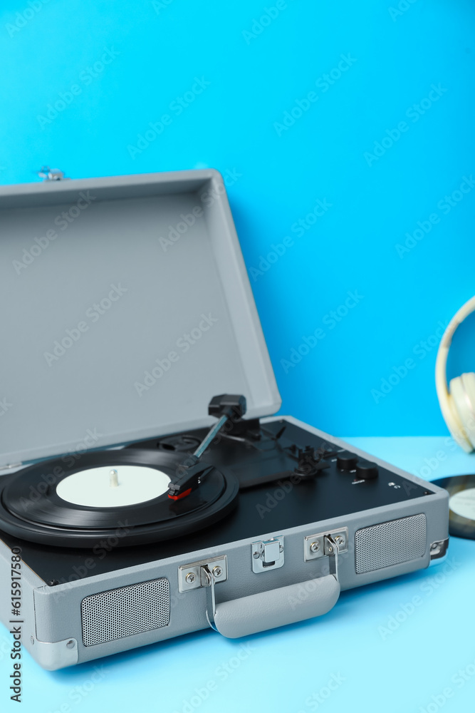 Record player with vinyl disk on blue table