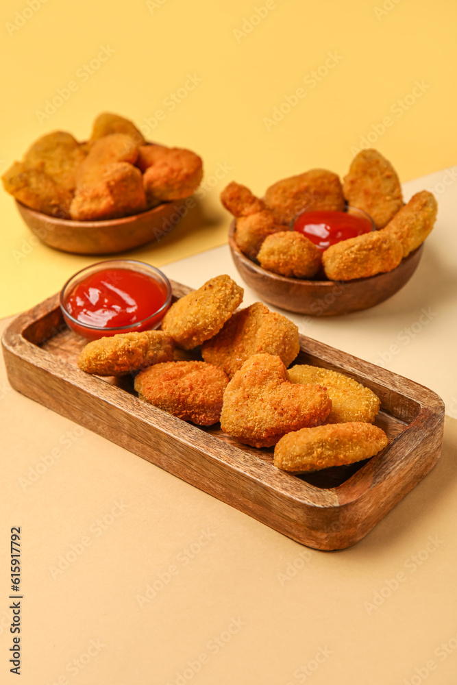 Wooden board with tasty nuggets and ketchup on color background