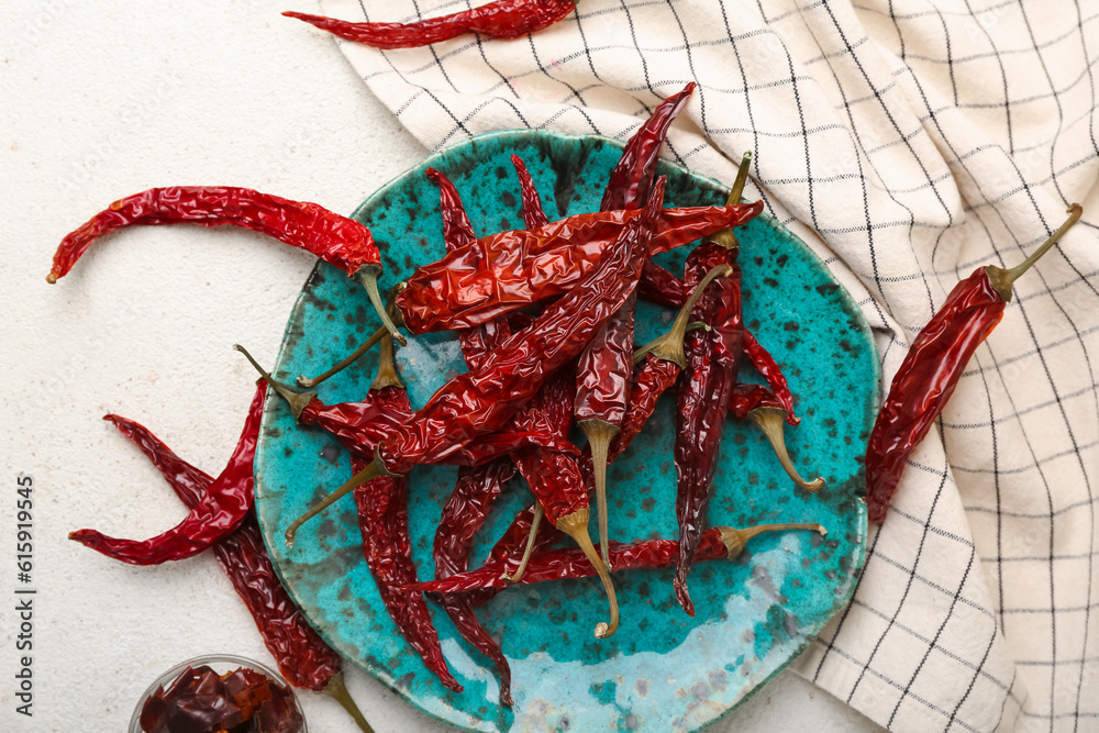 Plate with dry chili and bowl of sliced peppers on white background