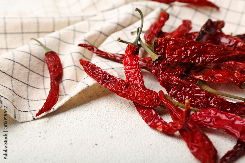 Dry hot chili peppers with checkered napkin on white background