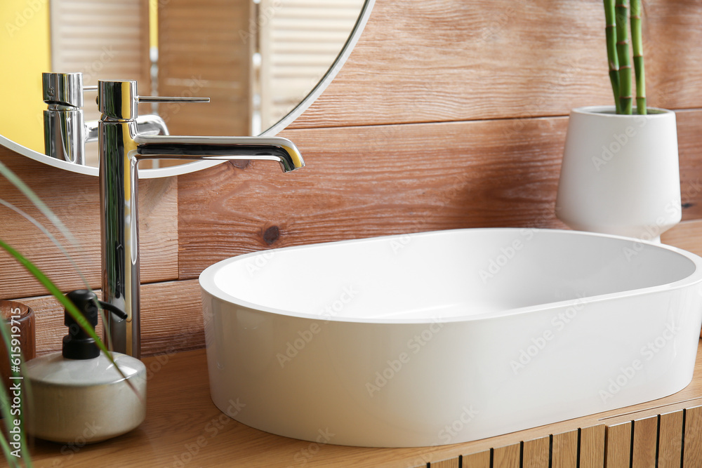 White sink with soap and vase on table in bathroom