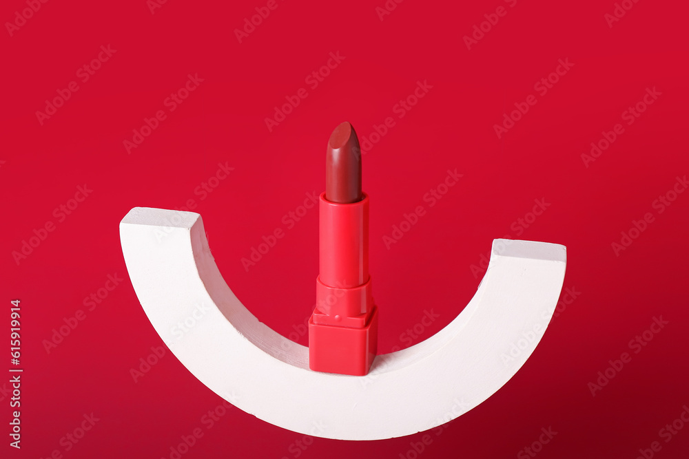 Decorative plaster podium and lipstick on red background