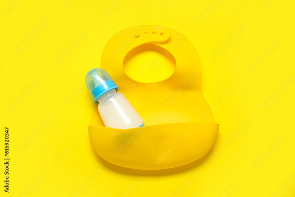 Bottle of milk with bib on yellow background