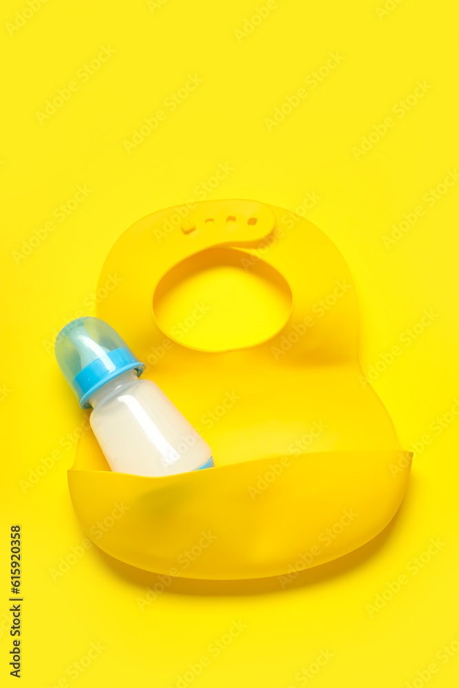 Bottle of milk with bib on yellow background