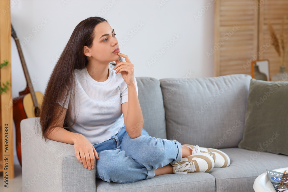 Thoughtful young woman on sofa at home