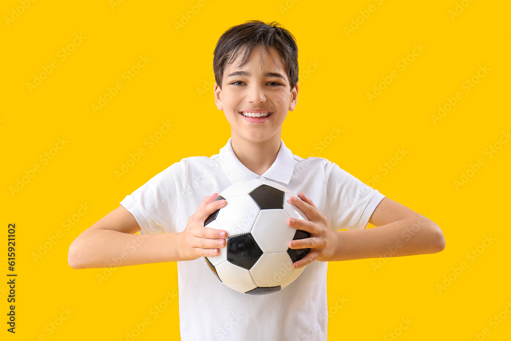 Little boy with soccer ball on yellow background