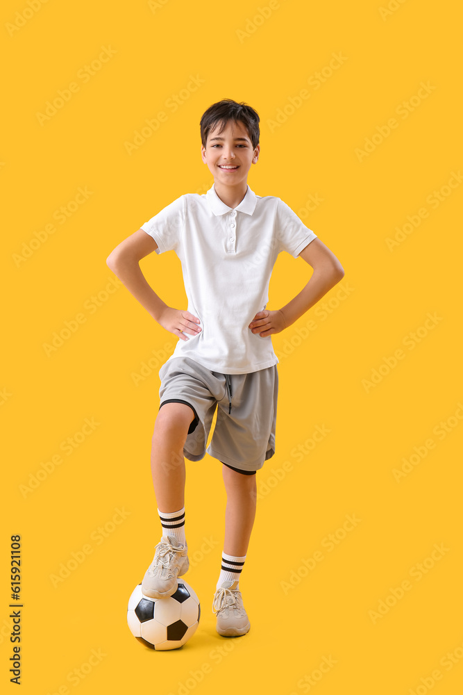 Little boy with soccer ball on yellow background