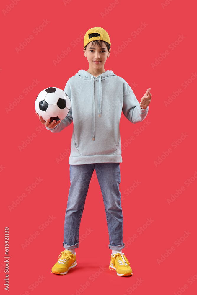 Cool little boy with soccer ball on red background