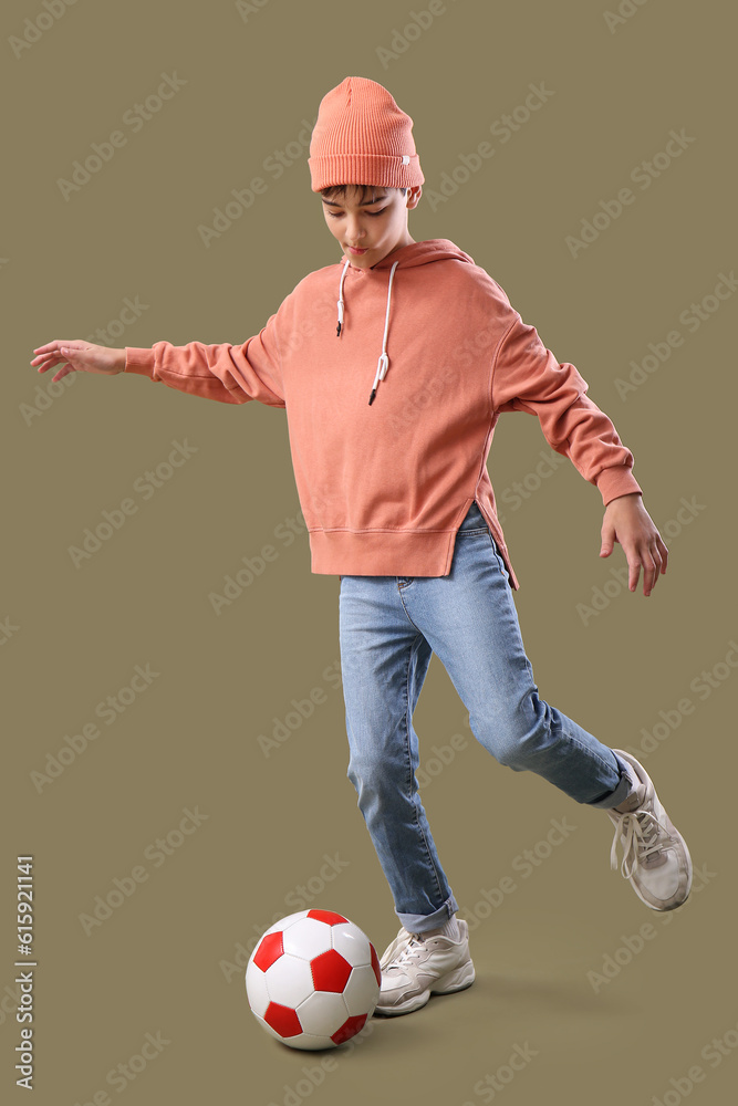 Little boy playing with soccer ball on color background