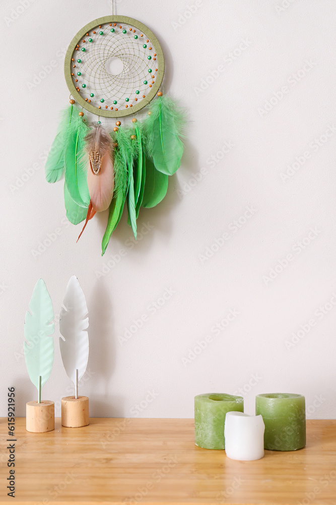 Dream catcher hanging on the wall above table and candles in living room