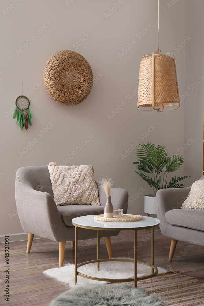 Interior of modern living room with armchair, coffee table and dream catcher hanging on grey wall