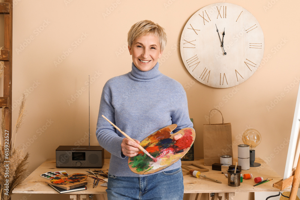 Mature female artist with palette and brush in  workshop