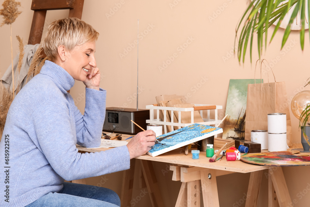 Mature female artist painting picture in  workshop