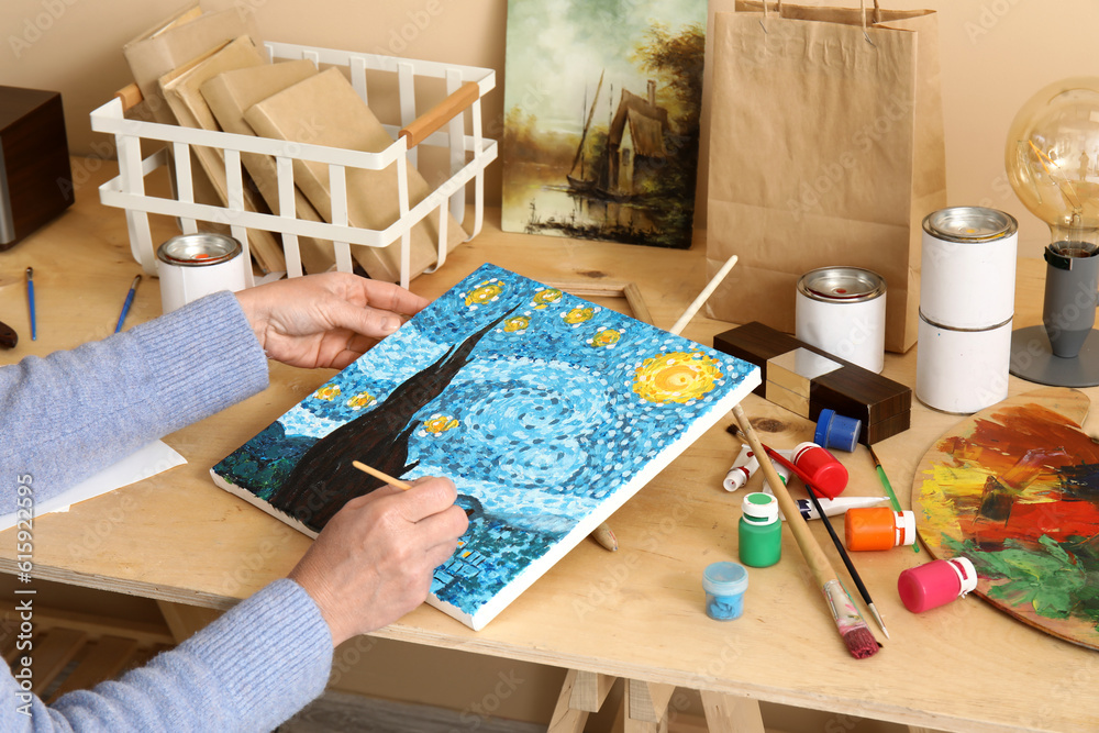 Mature female artist painting picture in  workshop