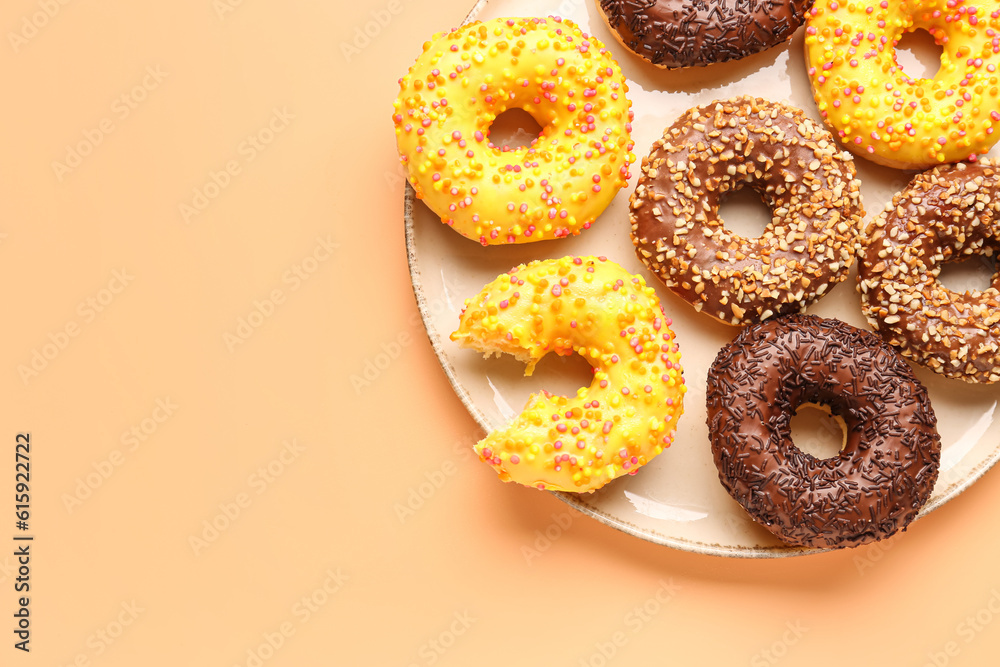 Plate with sweet donuts on beige background