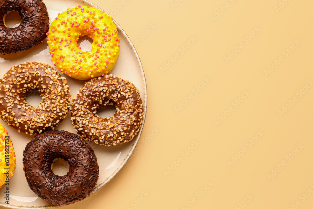 Plate with sweet donuts on beige background