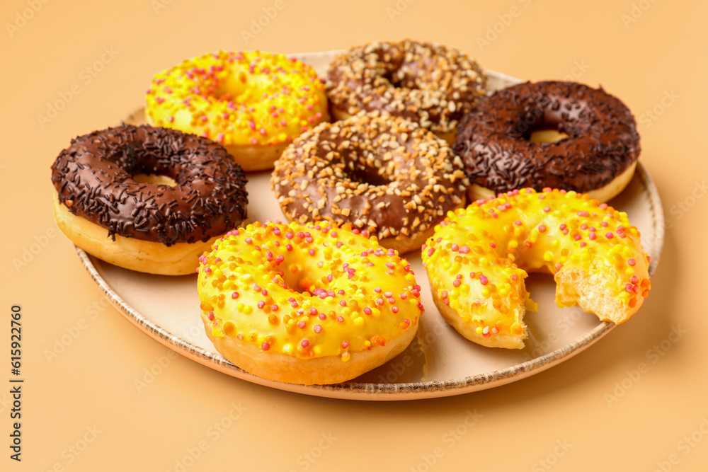 Plate with sweet donuts on beige background