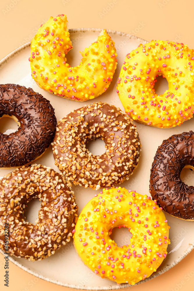 Plate with sweet donuts on beige background