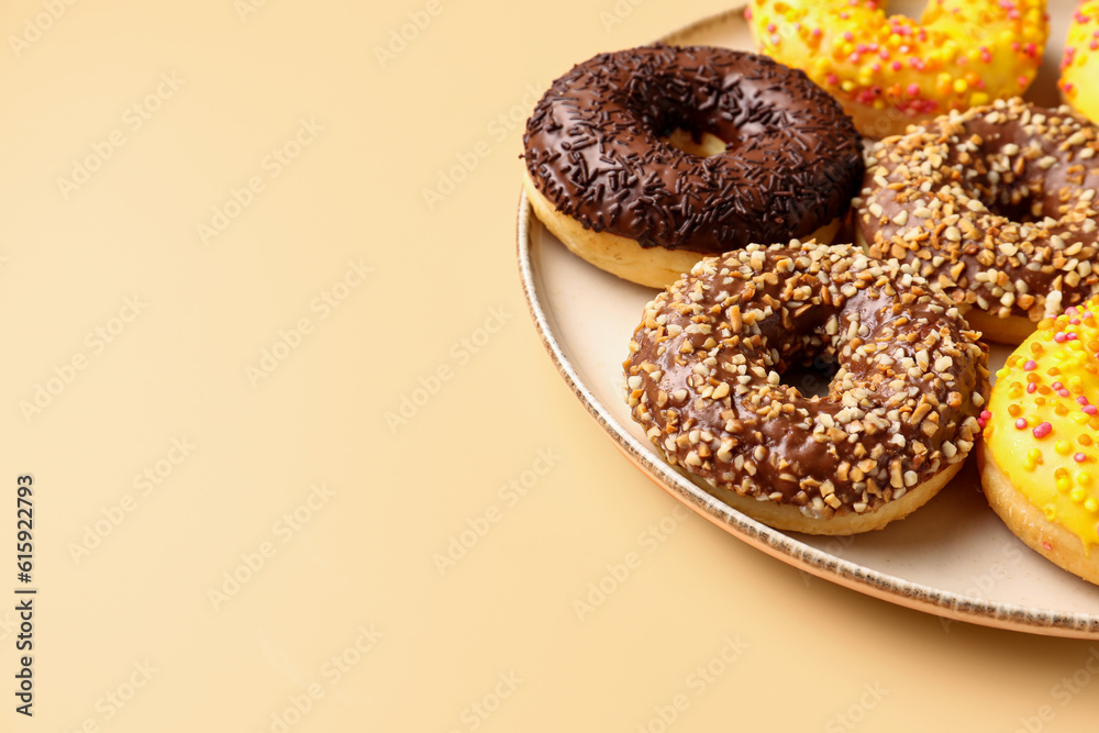 Plate with sweet donuts on beige background