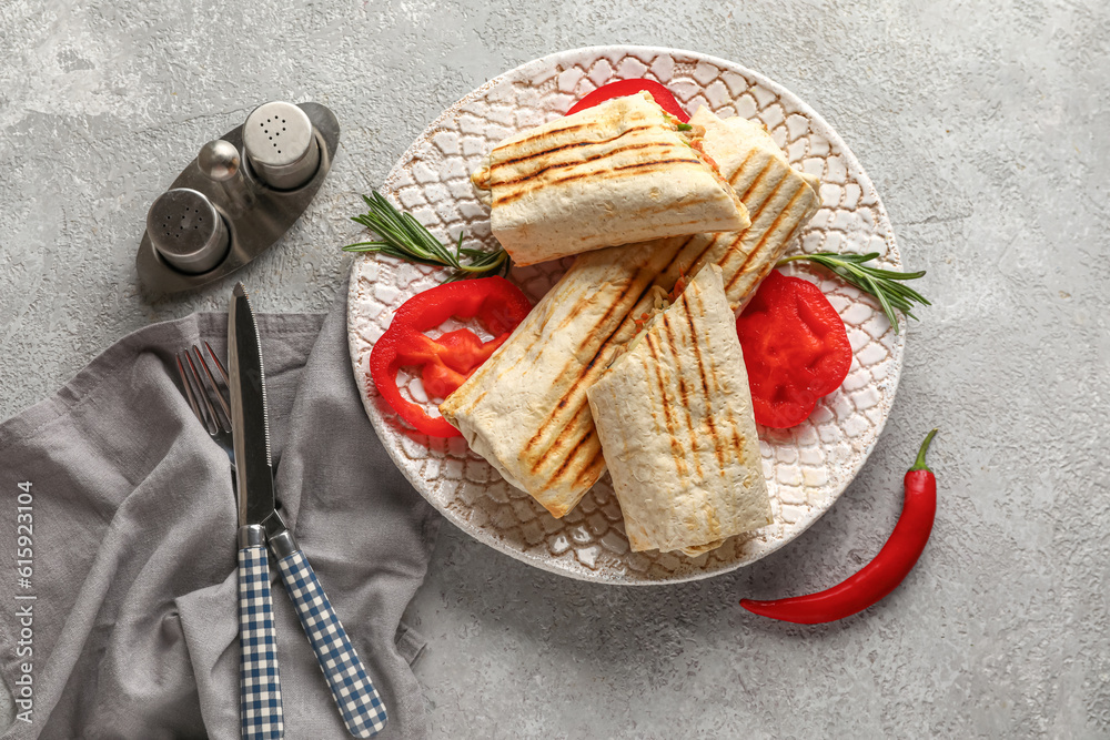 Plate with tasty shawarma and slices of bell pepper on grey table