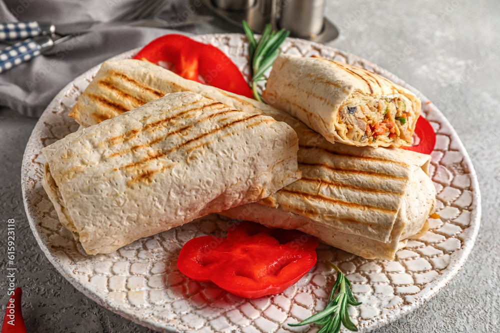 Plate with tasty shawarma and slices of bell pepper on grey table