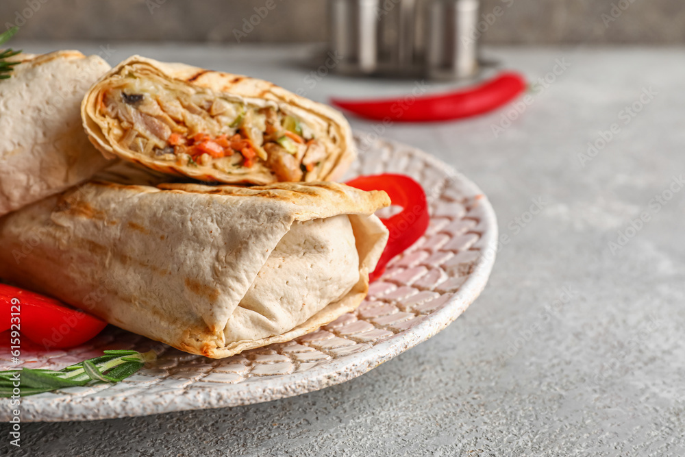 Plate with tasty shawarma and slices of bell pepper on grey table