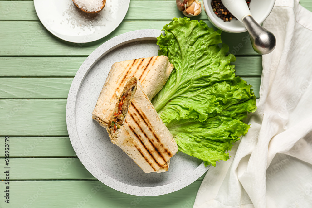 Plate of tasty shawarma with lettuce on green wooden background