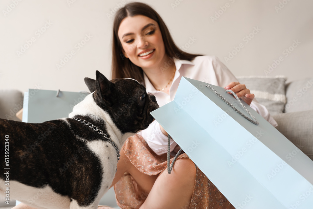 Young woman with shopping bag and her French bulldog at home