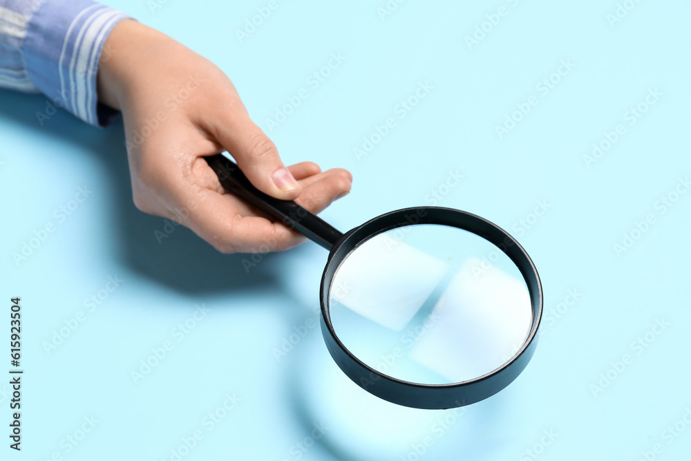 Female hand with magnifier on blue background