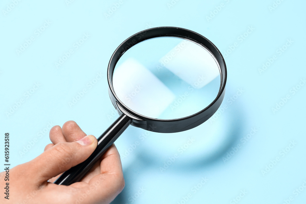 Female hand with magnifier on blue background