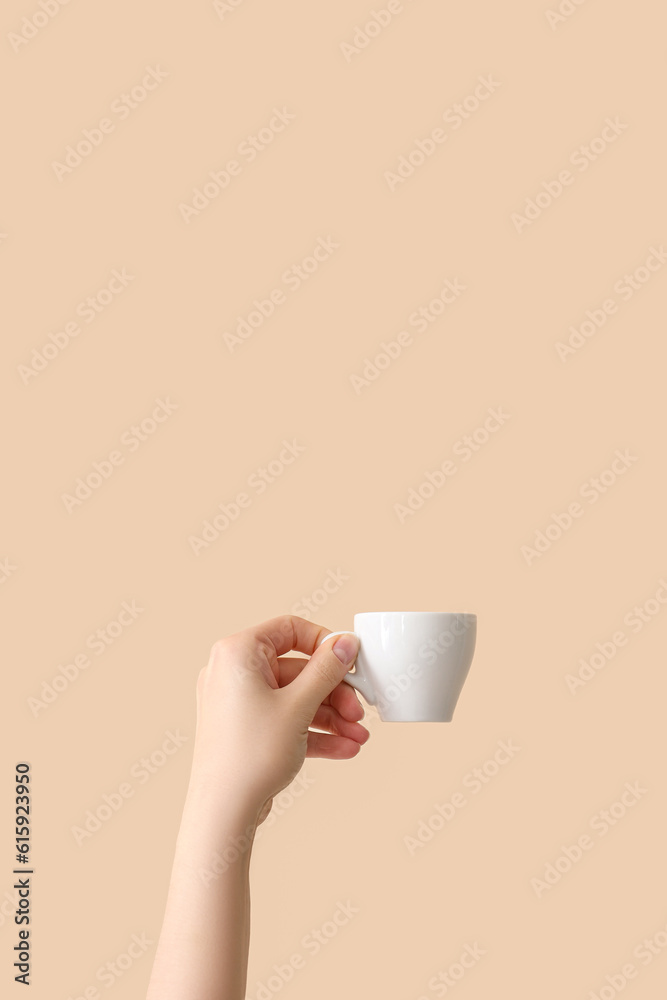 Female hand holding cup on beige background