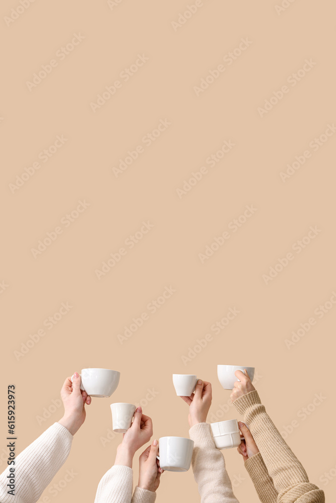 Female hands holding cups on beige background