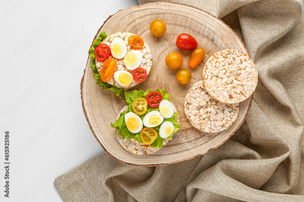 Rice crackers with quail eggs, tomatoes and lettuce on white background