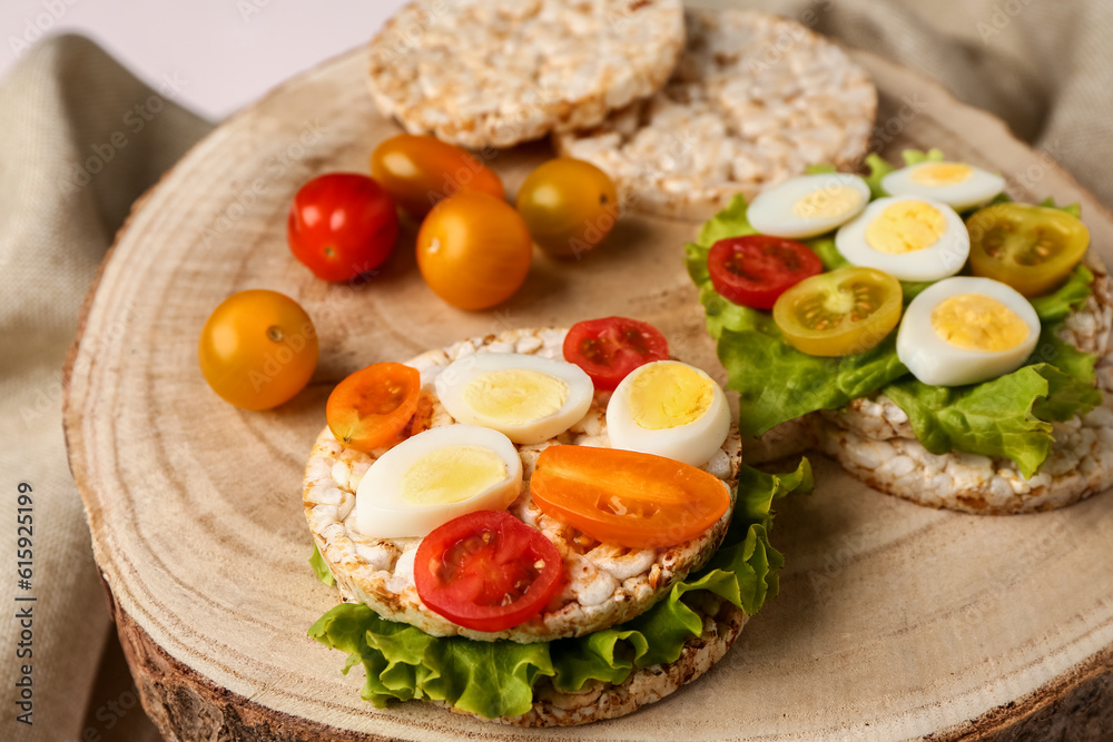 Rice crackers with quail eggs, tomatoes and lettuce on table, closeup