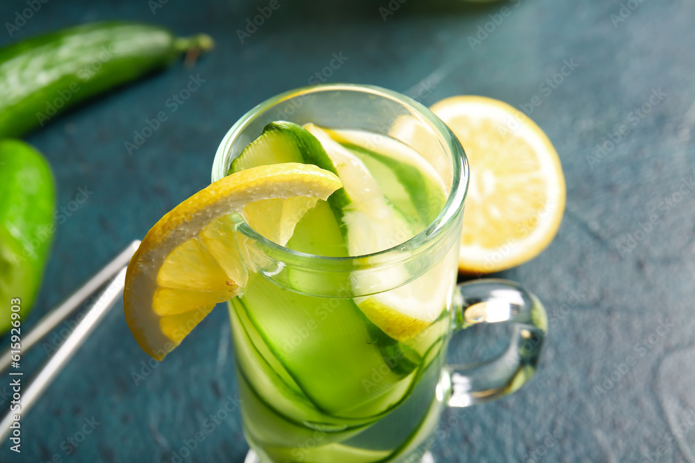 Glass of infused water with cucumber slices on dark table