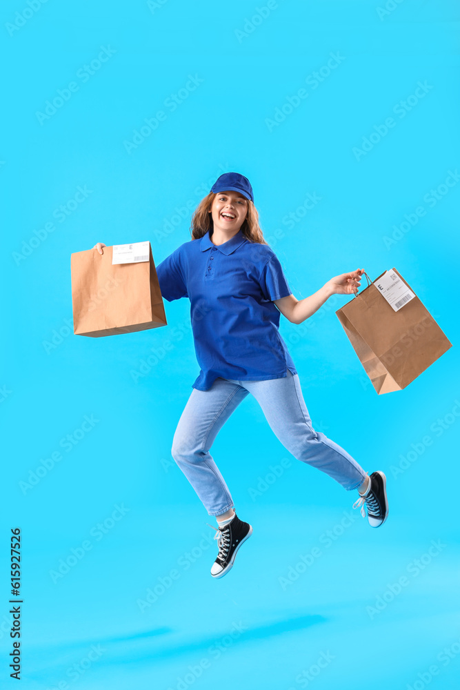 Jumping female courier with paper bags on blue background