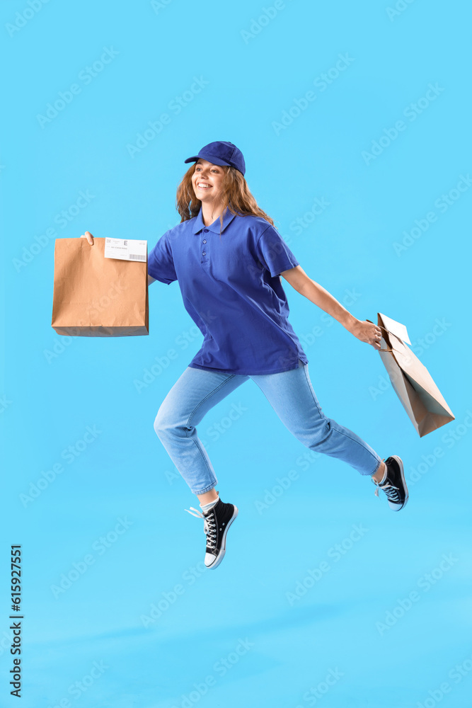 Jumping female courier with paper bags on blue background