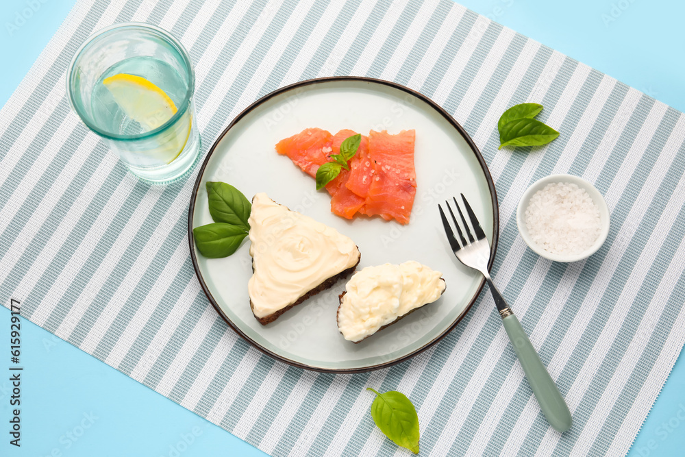 Tasty sandwiches with cream cheese and glass of water on blue background