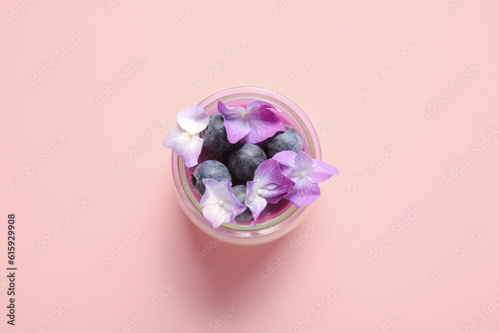 Glass of panna cotta with blueberry and beautiful hydrangea flowers on pink background