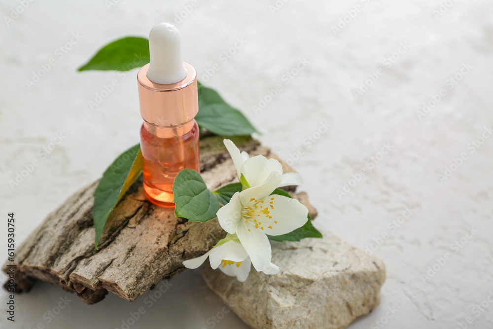 Bottle of cosmetic oil with jasmine flowers and tree bark on white background