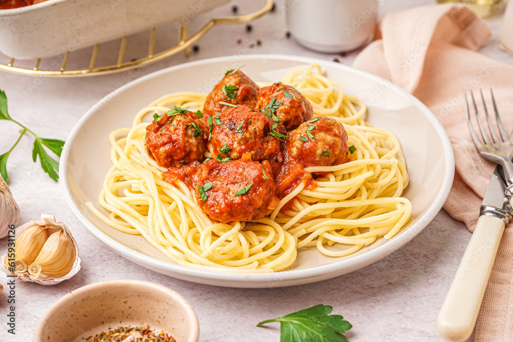 Plate of boiled pasta with tomato sauce and meat balls on white table