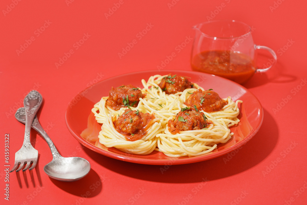 Plate of boiled pasta with tomato sauce and meat balls on red background