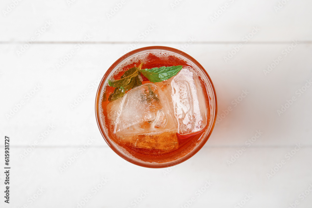 Glass of ice tea with mint on white wooden background