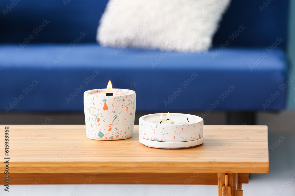 Holders with burning candles on table in room, closeup