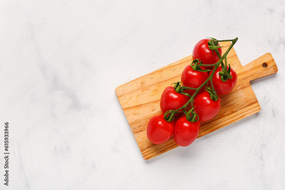 Wooden board with fresh cherry tomatoes on white background