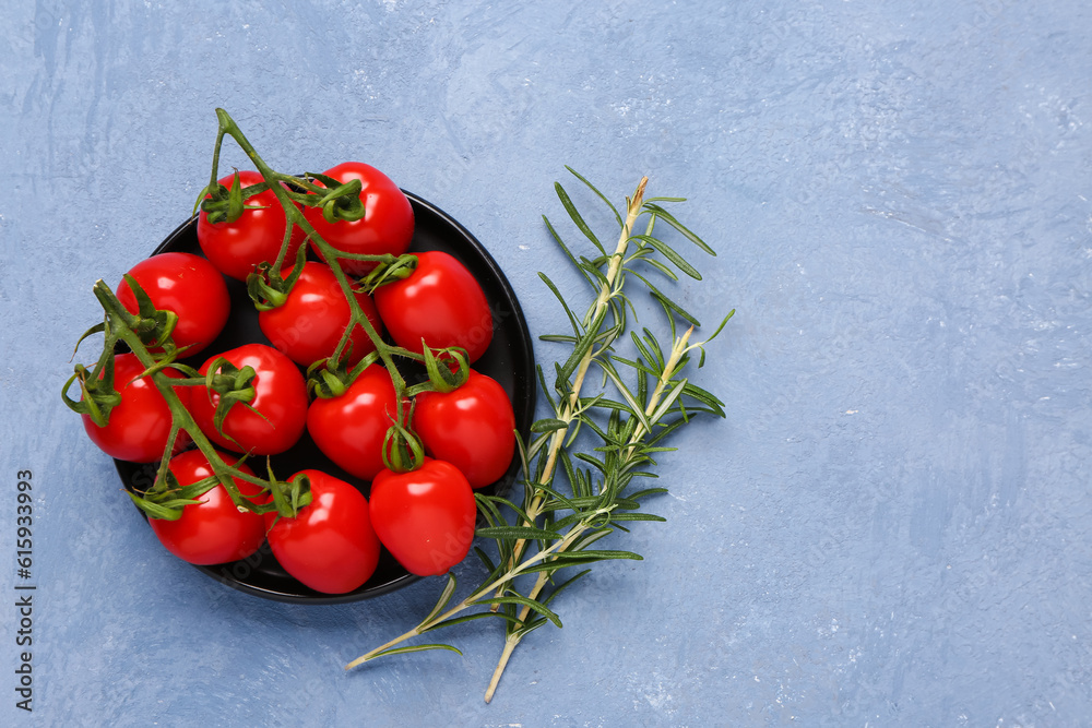 Tray with fresh cherry tomatoes and rosemary on blue background