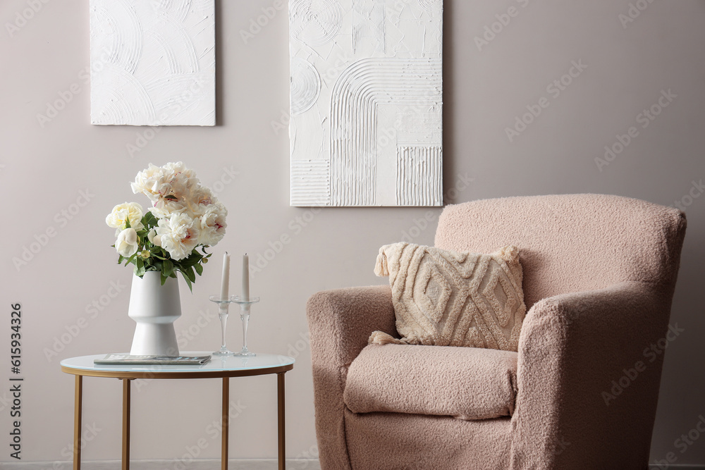 Vase of white peonies with coffee table and armchair near grey wall