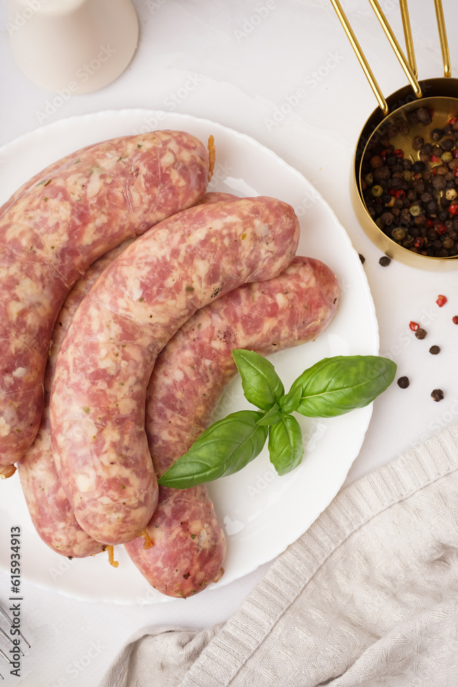 Plate with raw homemade sausages on light background