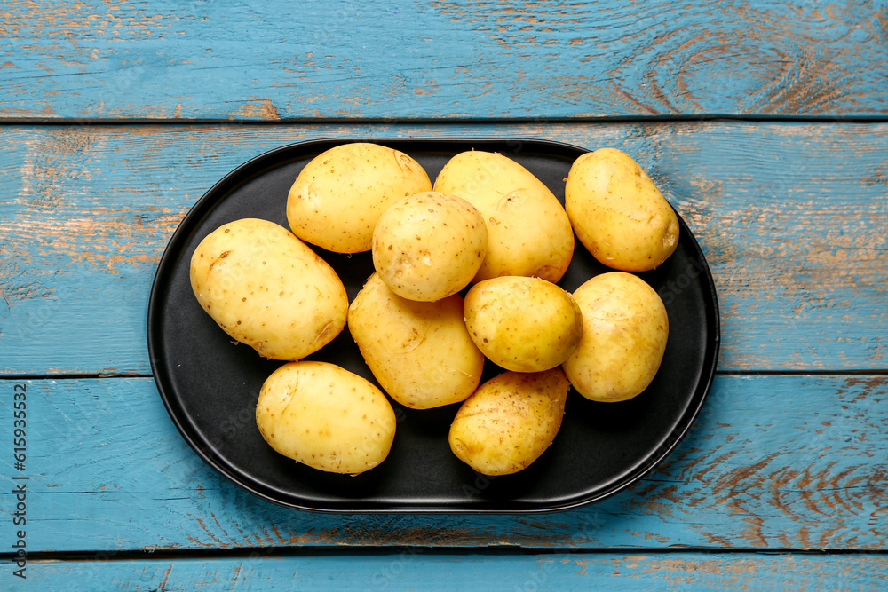 Tray with raw baby potatoes on blue wooden background